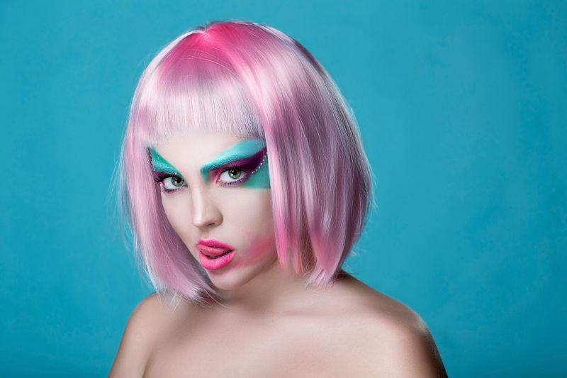 浅蓝色背景下画着创意妆容戴着粉色短假发的美女