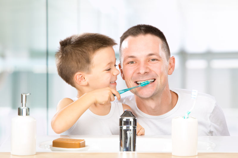 帮助父亲刷牙的小男孩
