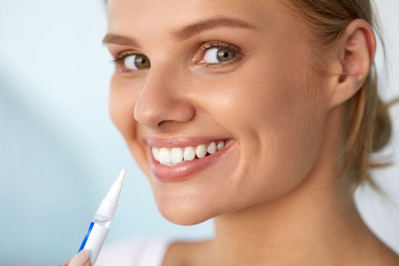 微笑的女人用白色牙齿美白笔