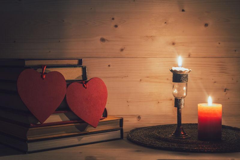 木制背景中的两颗红心和燃烧的蜡烛