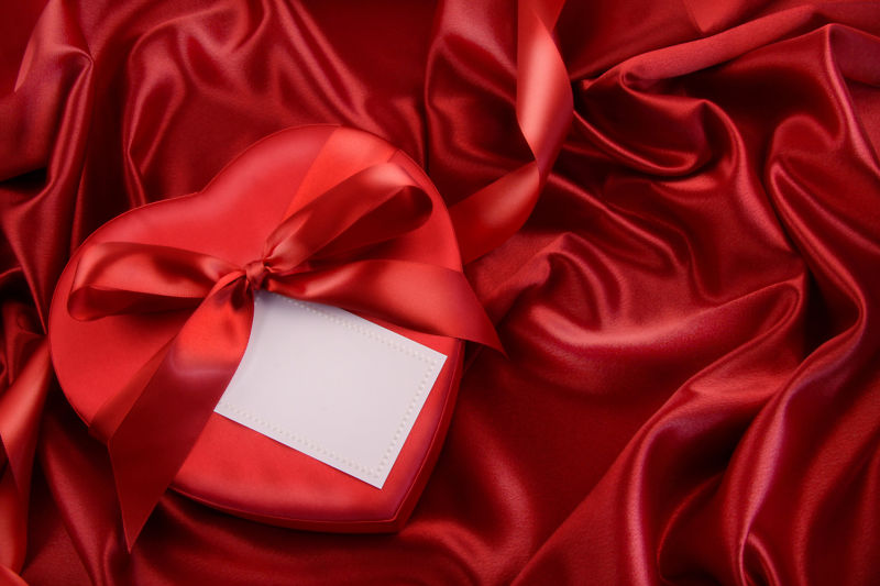 红色丝绸背景中的礼物和卡片