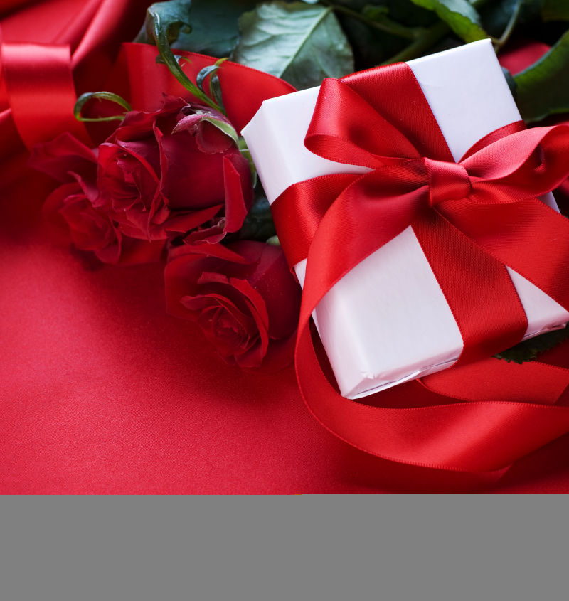 红色背景中带有蝴蝶结的礼物盒和红色玫瑰