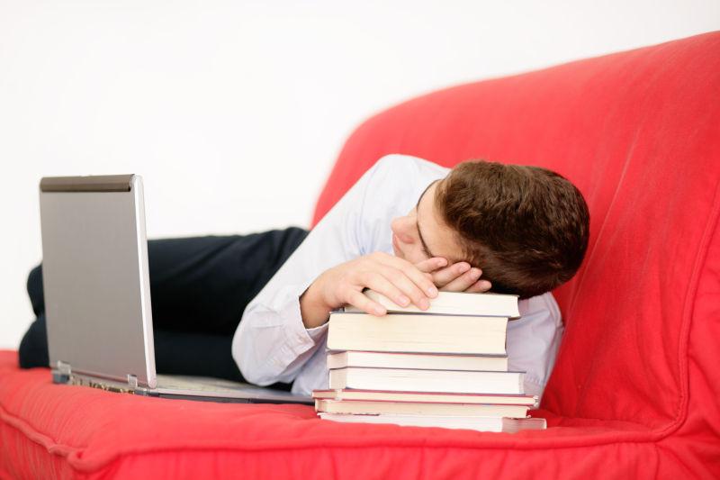 沙发上玩笔记本睡着的男人靠在书本上
