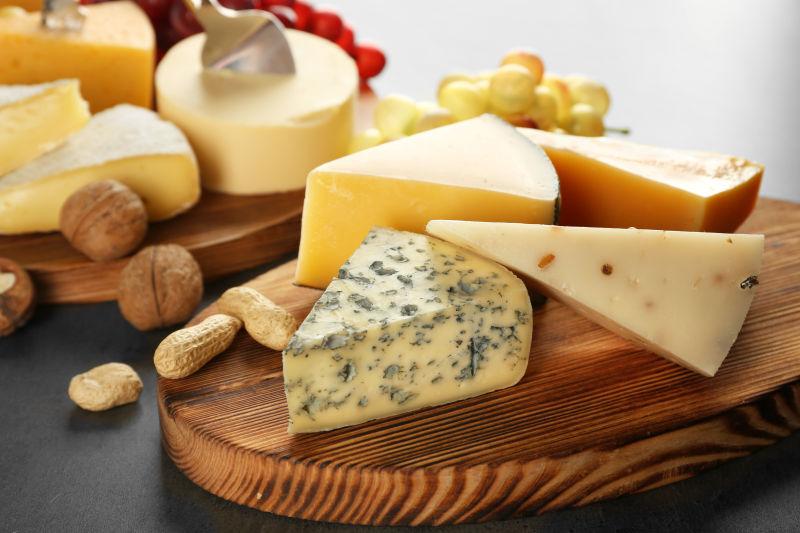 灰色背景中各种奶酪和坚果的木板