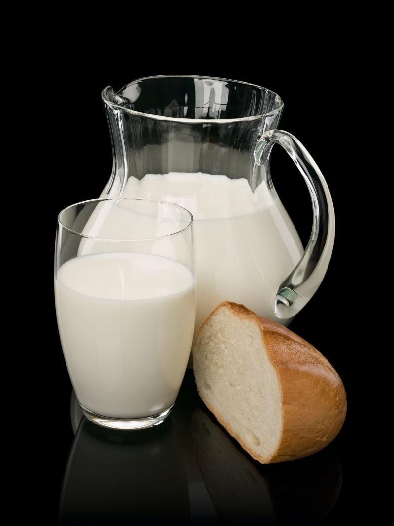 黑色背景中的色的面包块和玻璃杯被牛奶填满