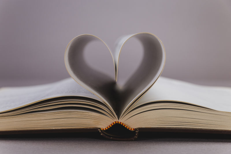 木桌上打开的书页折叠成的爱心书籍