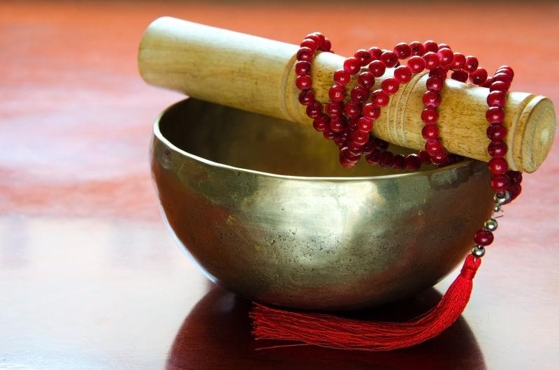 木制桌上的一个藏式碗和红色马拉珠子