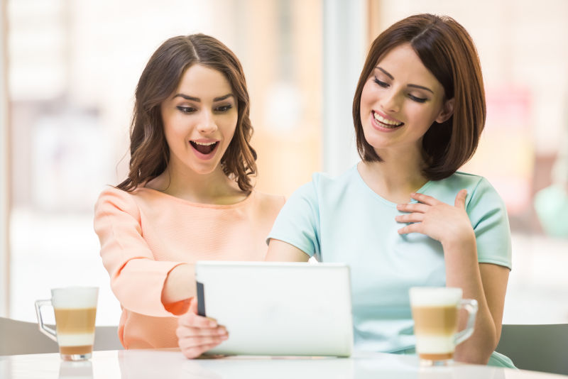 两个女性朋友在开心的看平板电脑