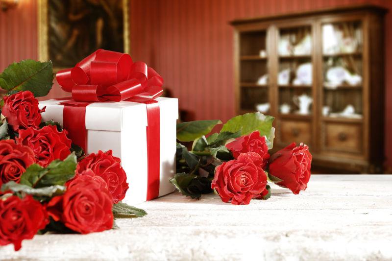 白色桌子上的玫瑰花与礼盒