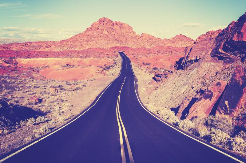 蓝天下群山之中的老式曲线沙漠公路