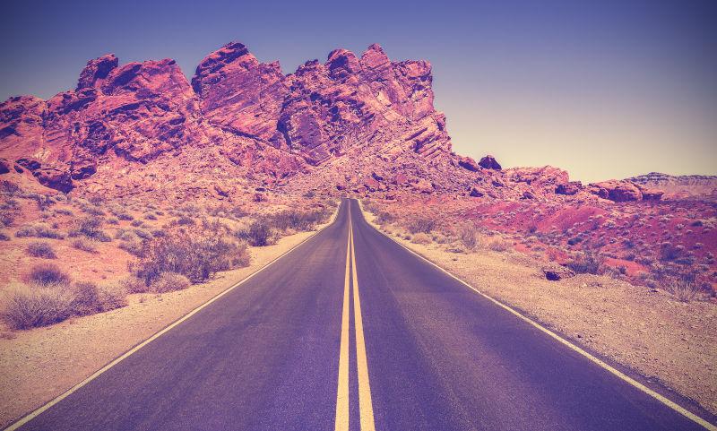 蓝天下群山中的内华达州石漠沙漠的复古风格道路