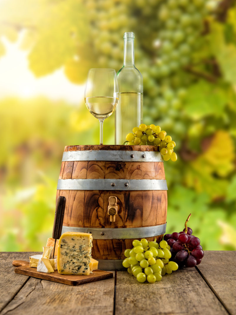 木板上的葡萄和木桶上的白葡萄酒