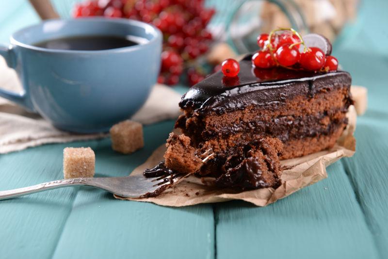 美味的巧克力蛋糕配上浆果和茶杯在木桌上