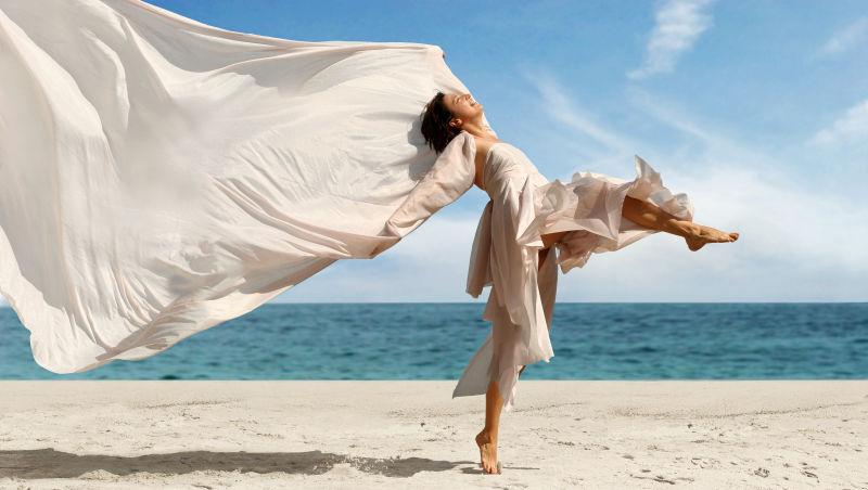 沙滩上美女飘荡的白色丝绸裙子