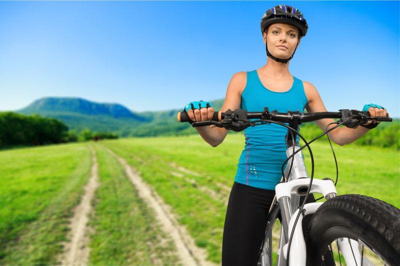在田野里骑自行车戴头盔的女人