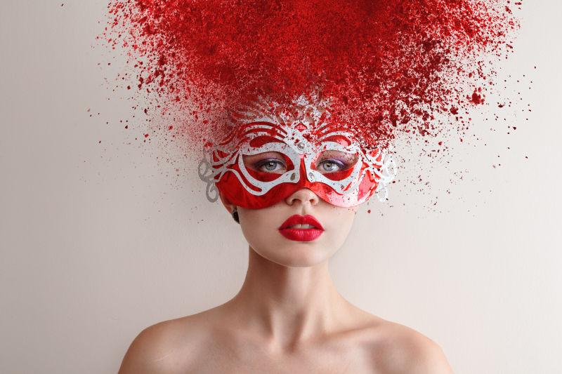 带狂欢面具和红色抽象发型的女模特