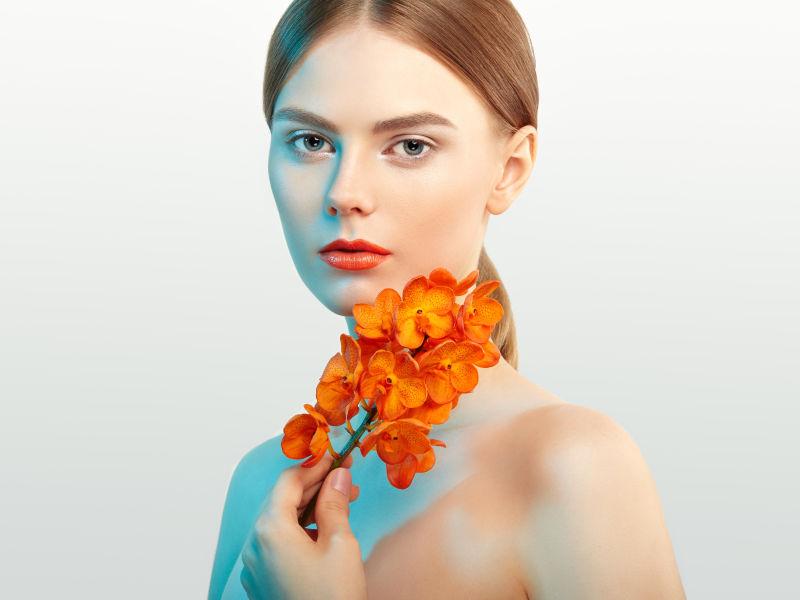 美丽的年轻女子拿着橙色兰花