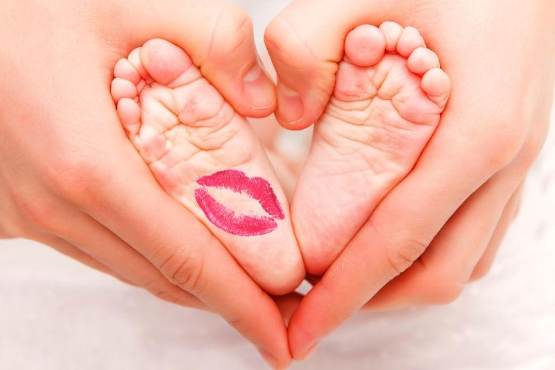 母亲的手婴儿的脚上的口红印