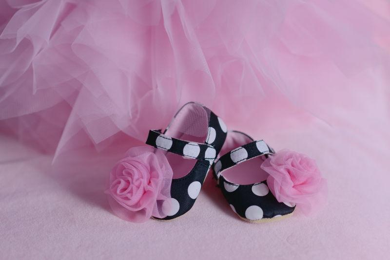 粉红色的薄纱旁边可爱的婴儿鞋