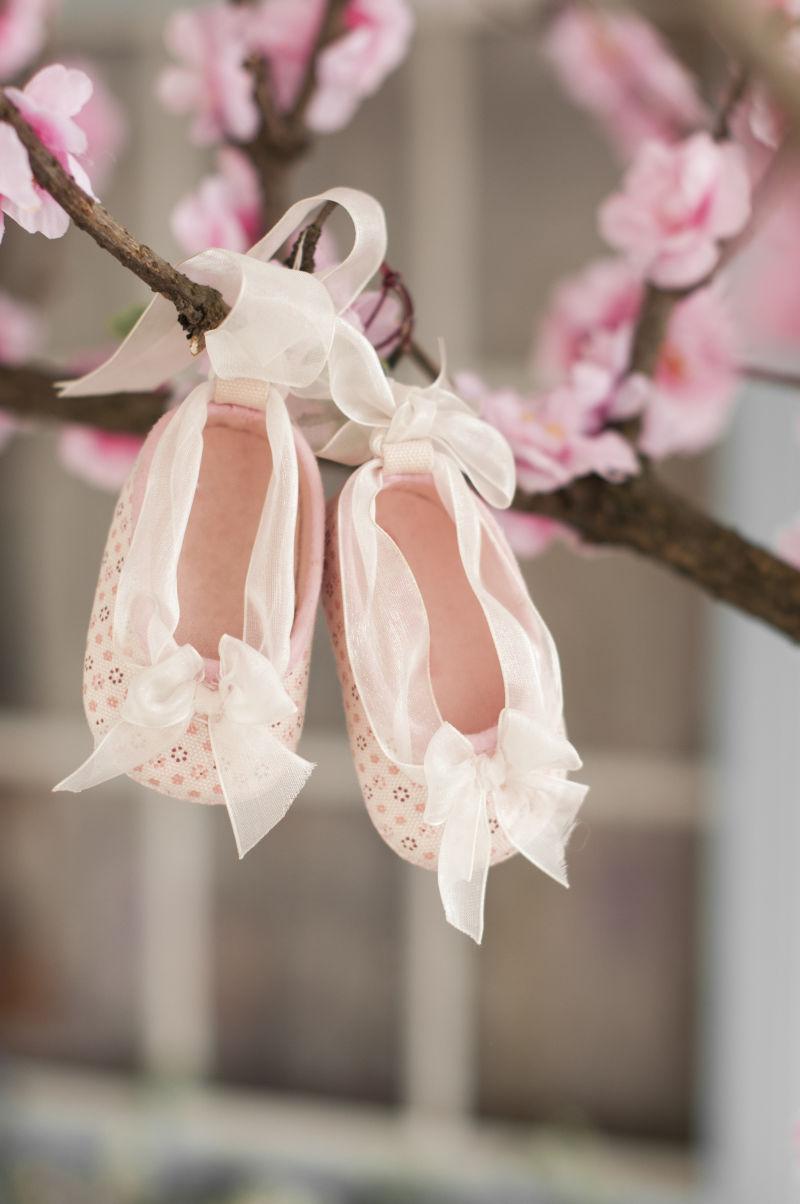 绑在桃树上带蝴蝶结的粉红色婴儿靴