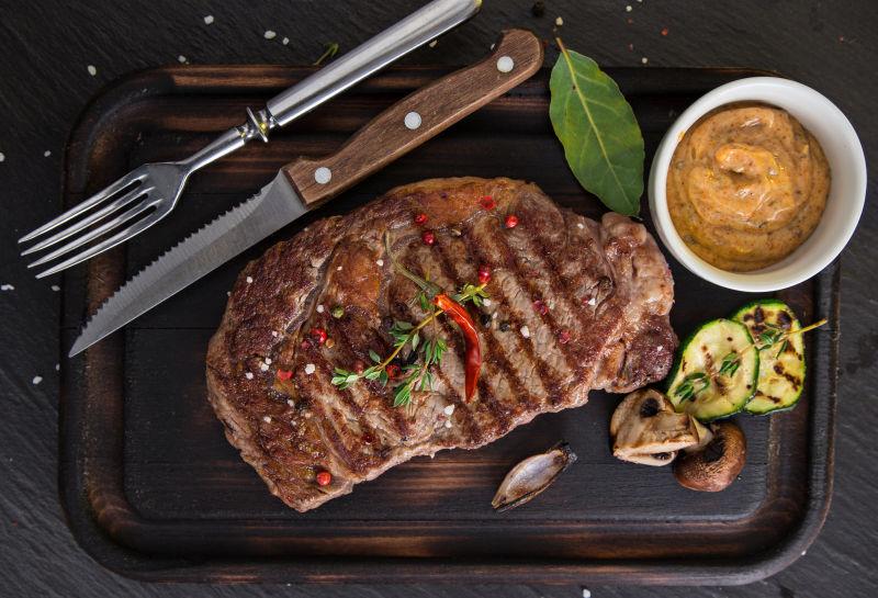 木桌上的刀叉和美味的牛排