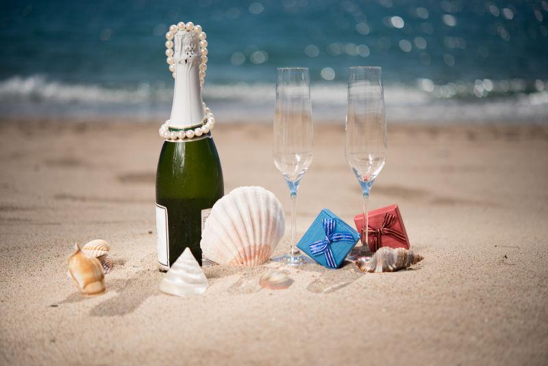瓶装香槟在海滩上有礼盒和贝壳