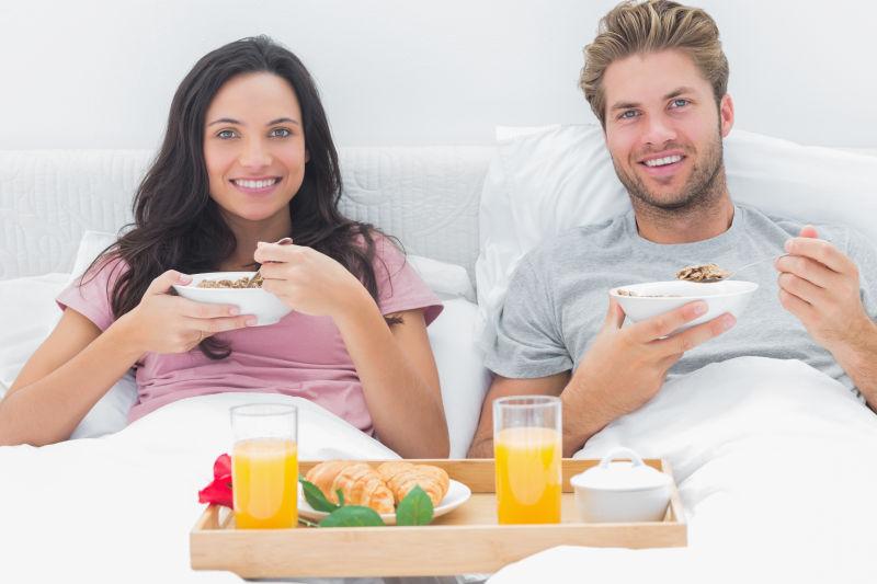 在床上享受早餐的浪漫夫妇