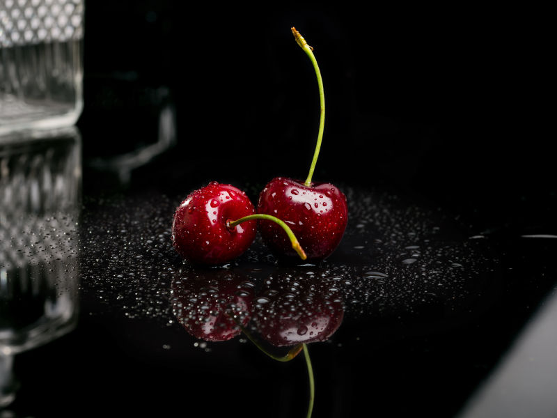 黑色桌子上两颗沾水的樱桃