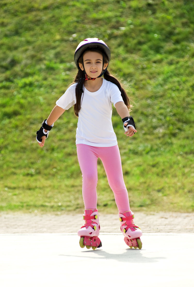 戴着护具在小路上玩溜冰鞋的小女孩