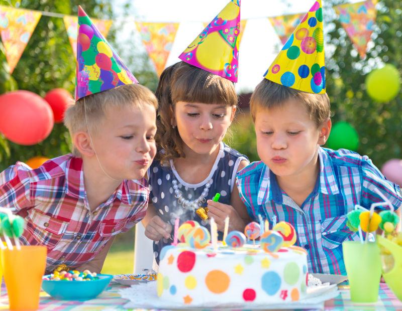 孩子们在蛋糕上吹蜡烛庆祝生日派对