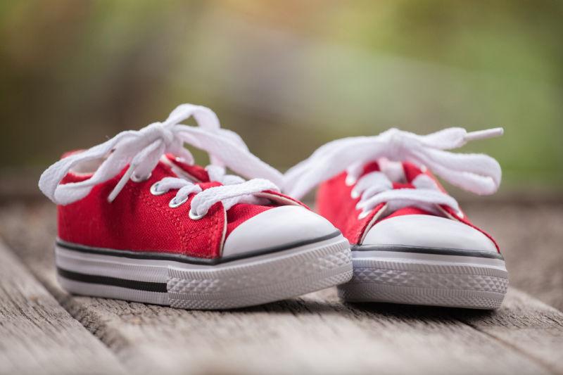 木制背景下红色婴儿运动鞋