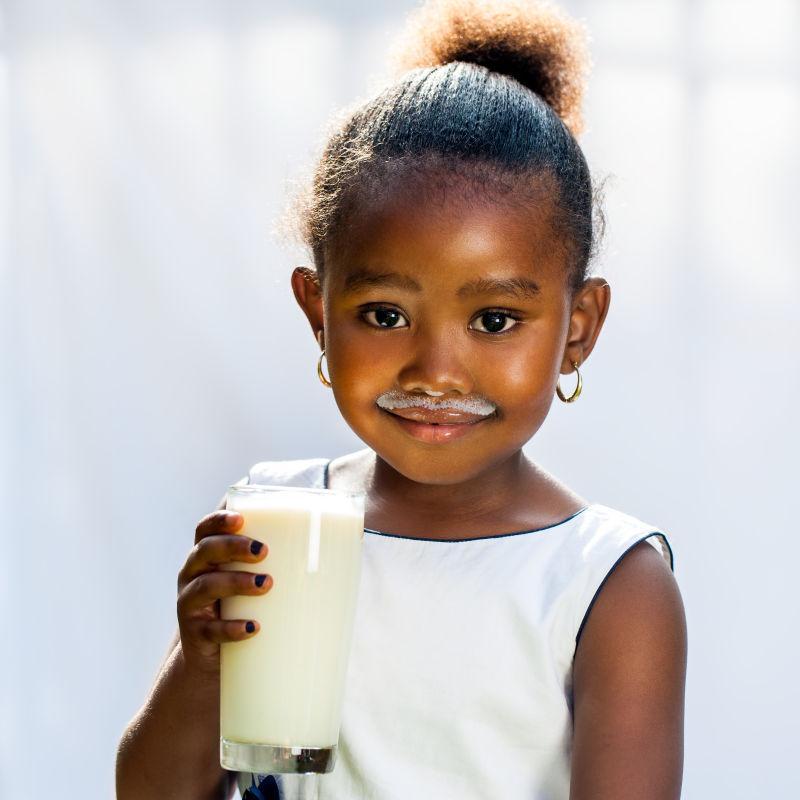 可爱的非洲女孩喝着一杯牛奶