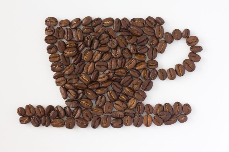 白色背景上摆成咖啡杯形状的咖啡豆
