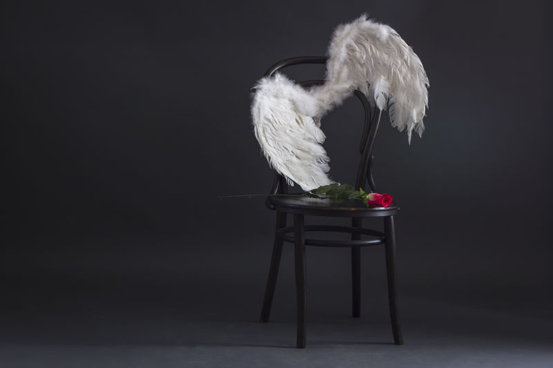 白色天使翅膀孤独地挂在复古椅上