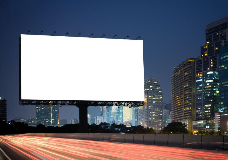 夜幕时分城市背景下的高速公路上的空白广告牌