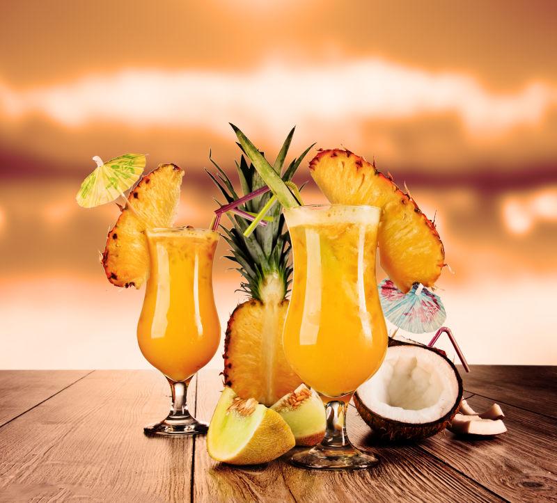 橘色背景下木桌上菠萝和椰子制作的鸡尾酒