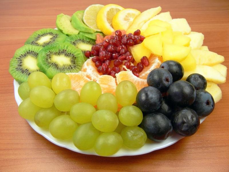 木桌上白色盘子里的各种美味水果