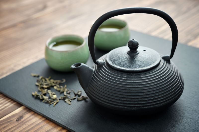 黑色垫子上的茶壶和茶叶