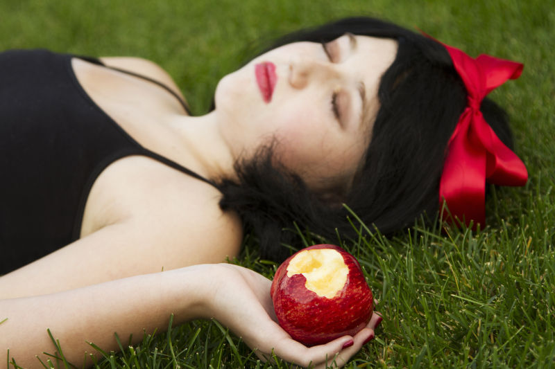 躺在草地上的女子手拿一个咬过的苹果