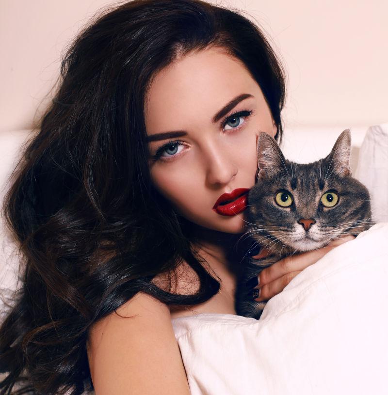 躺在床上抱着一只猫的美女