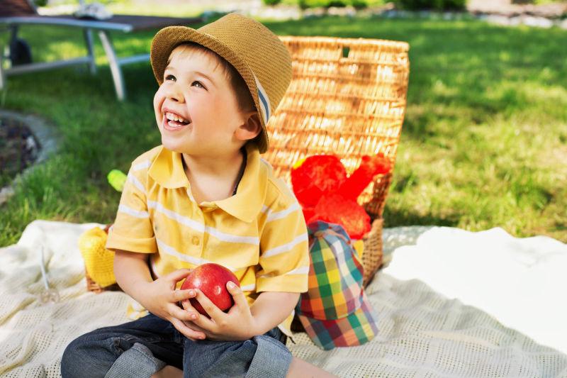 微笑的小男孩拿着一个苹果