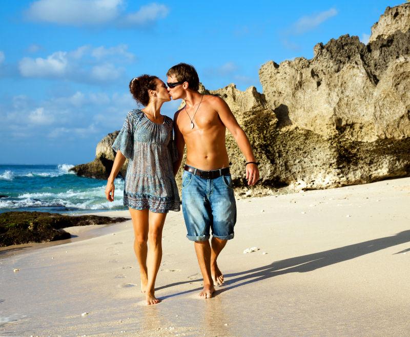 在海滩上散步亲吻的情侣