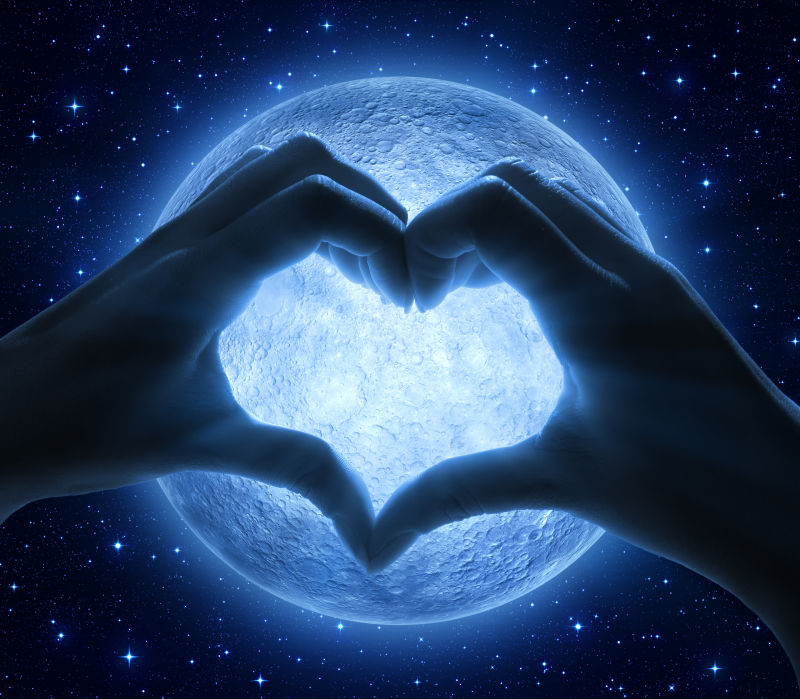 月亮背景前将手拼成爱心形状