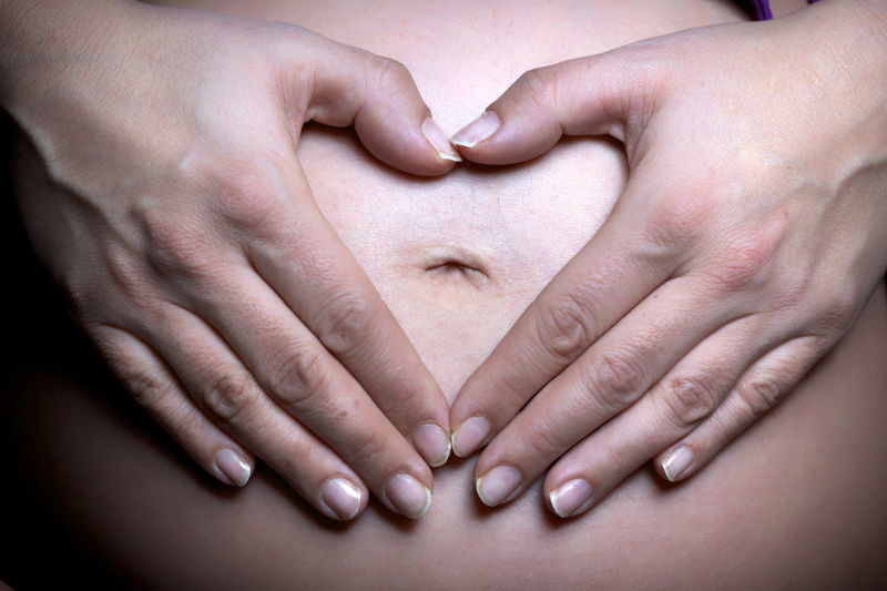 孕妇在肚子上做着爱心的手势