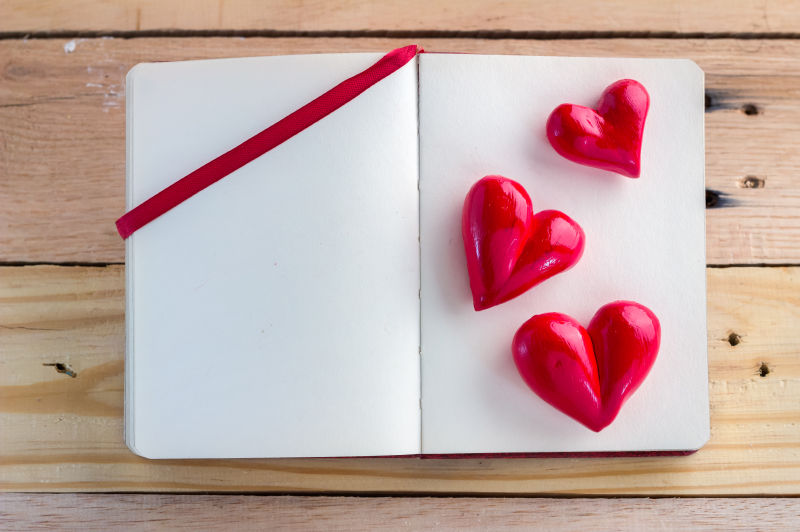 木质地板上情人节笔记本上的红心概念