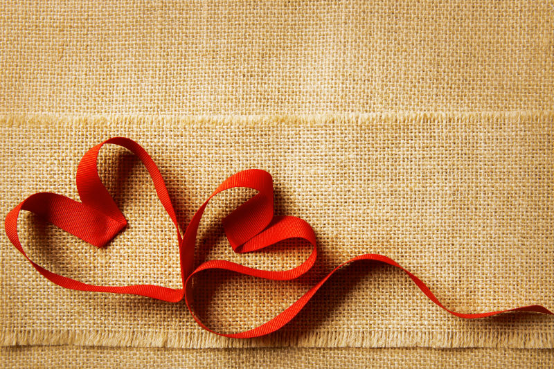 麻布背景上的红色丝带心形