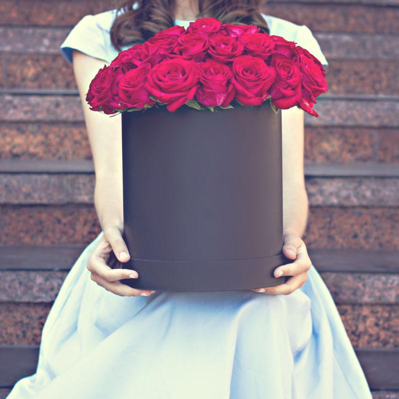 女孩手拿一盒红色玫瑰花