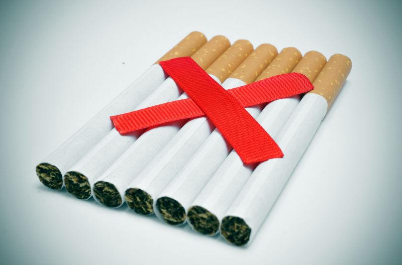 一堆香烟和两条交叉的红色斜线描绘了禁止吸烟的概念