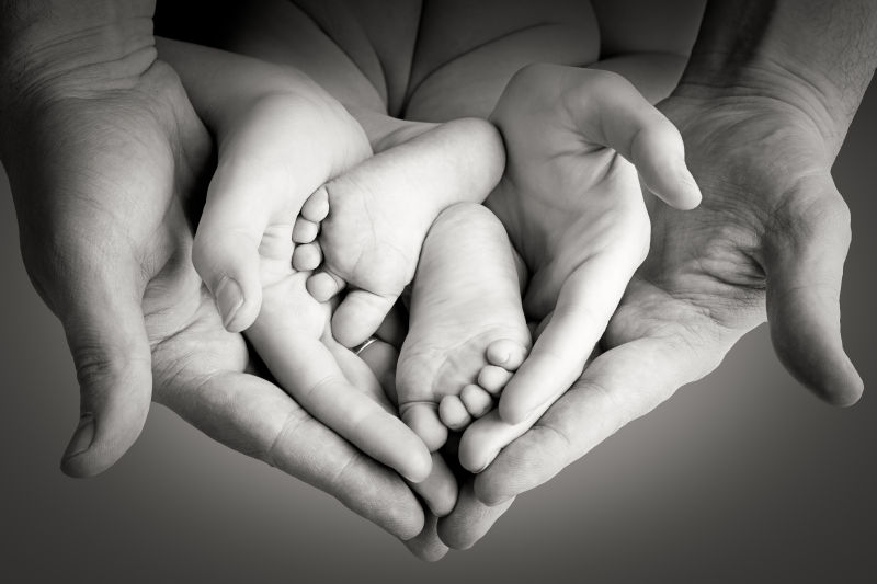 年轻夫妇的手和婴儿的脚