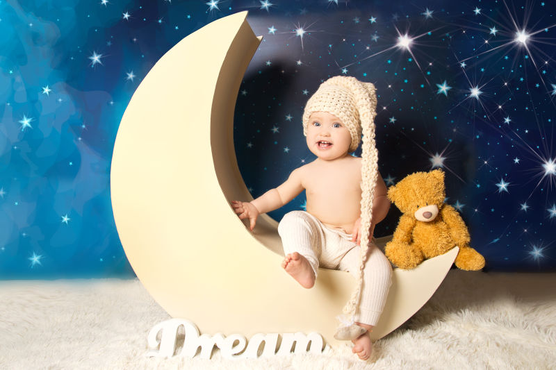 坐在月亮模具上的宝宝与小熊玩偶